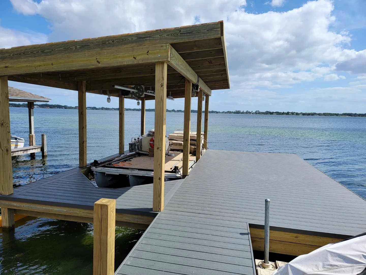 A wooden dock with a boat lift structures and a boat nearby on a lake, dock builder on lake Conway, Orlando, Florida
