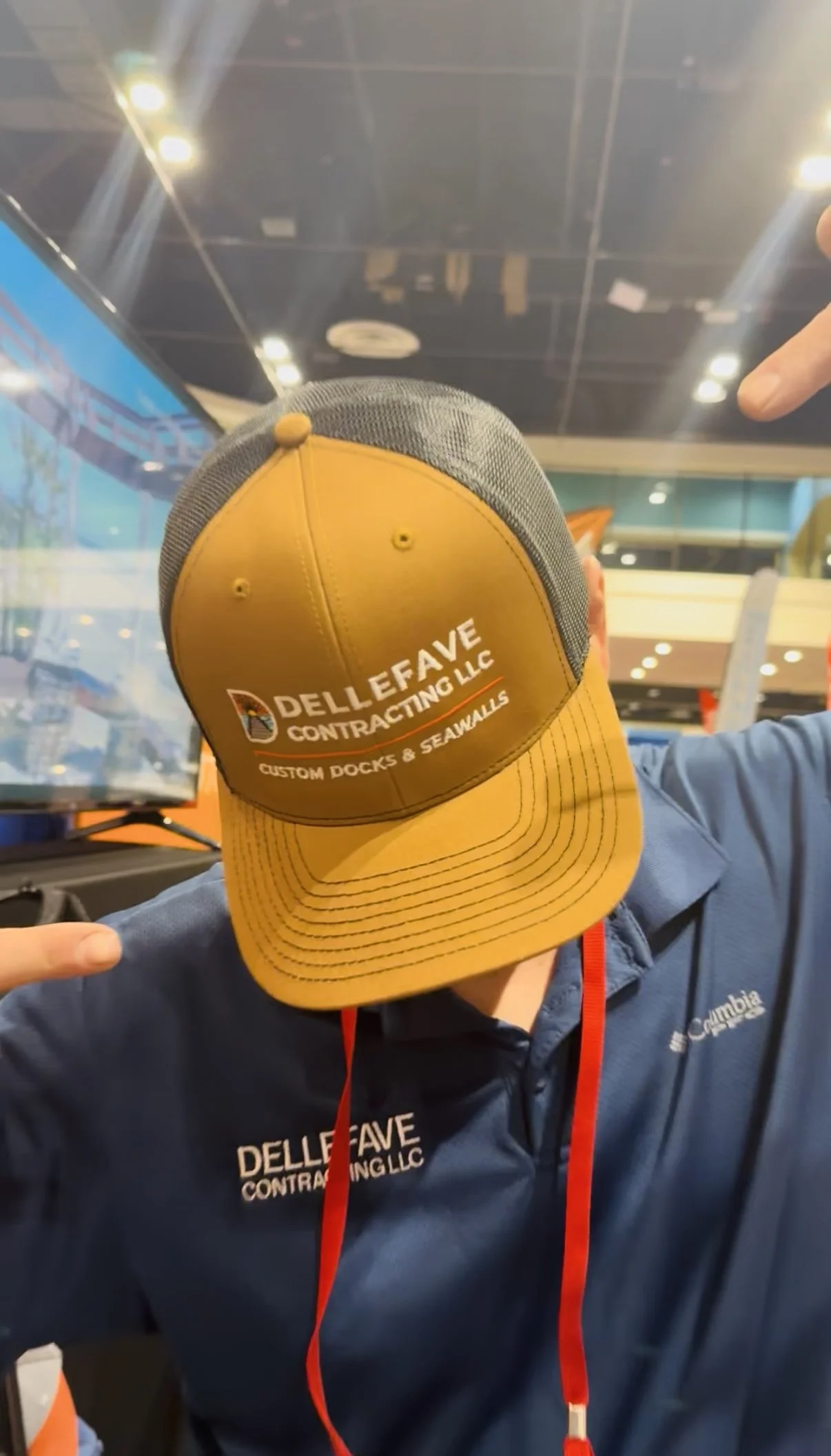 Person wearing a snapback cap with the logo of DelleFave Contracting LLC, at Orlando Boat show selling docks, seawalls, boat lifts, gazebos.