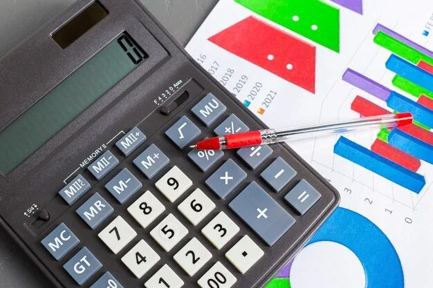 Calculator with a red pen resting on it and colorful financial charts and graphs on paper.