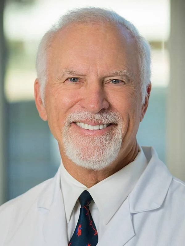 Elderly man with white beard wearing a white coat and tie