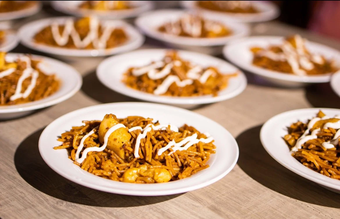Multiple white plates of seasoned fried rice with toppings of sauce, arranged on a wooden table.