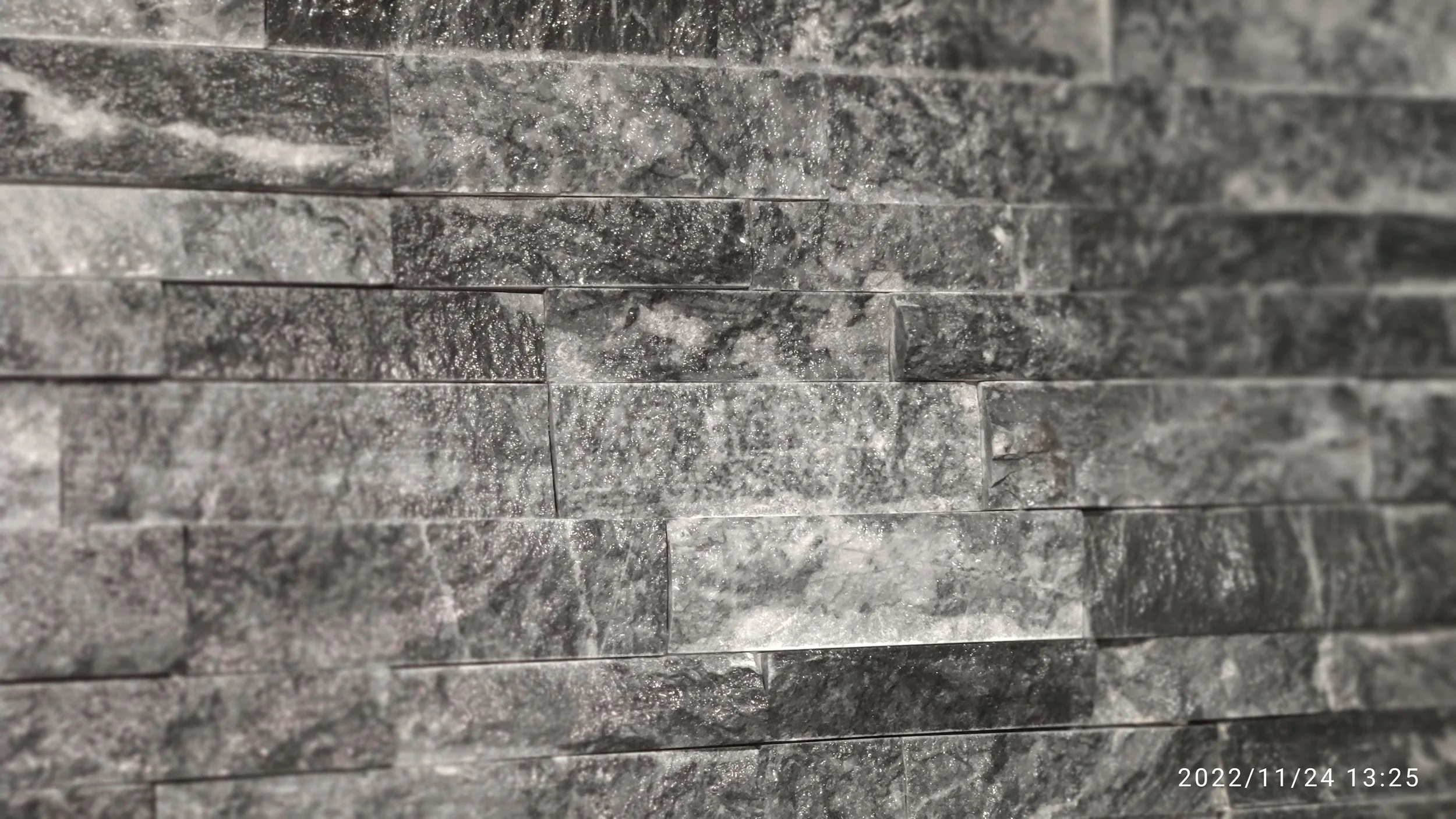 Close-up of a textured, dark gray granite tile wall.
