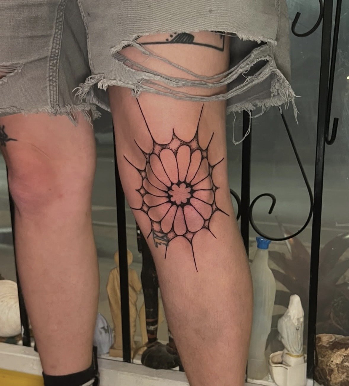 Tattoo of a spider web design on the person's right thigh.