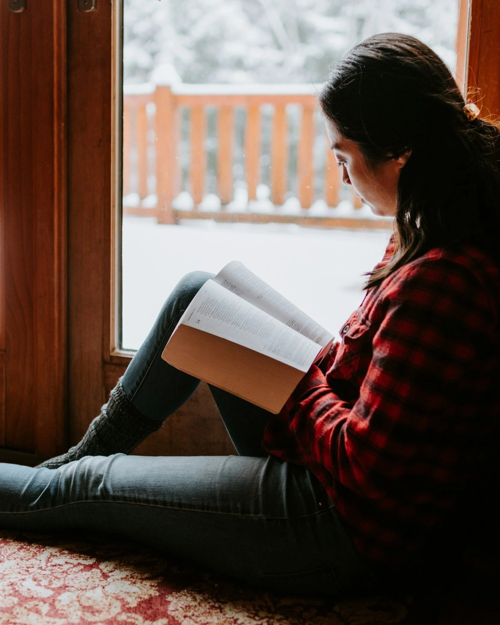 Woman reading in front of a window in winter