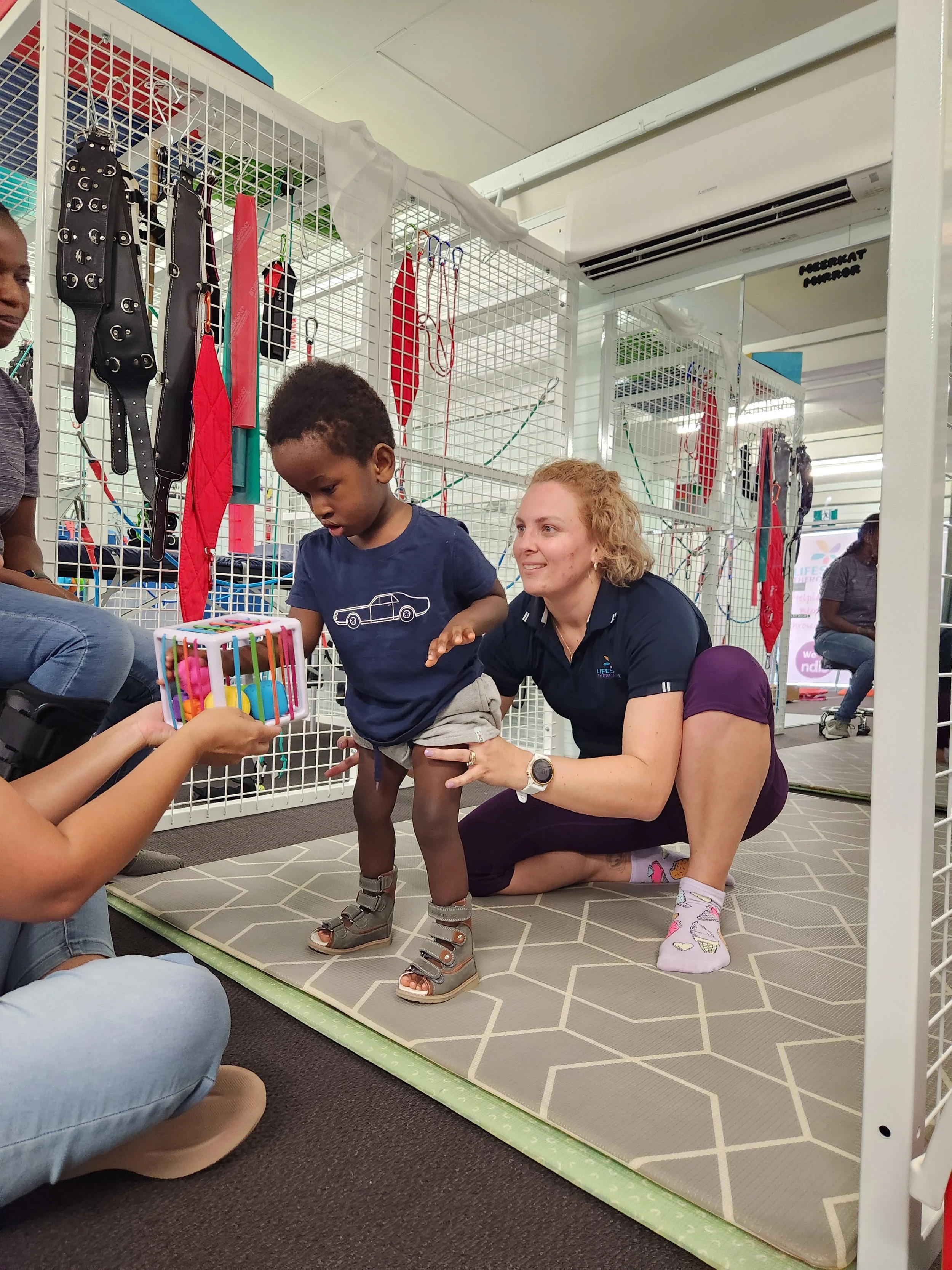 Physiotherapist Liz Donnellan working with children and children with disabilities at Lifespan Therapies in Strathpine, North Brisbane. Pictured with a child, both are smiling in the Lifespan Therapies gym.