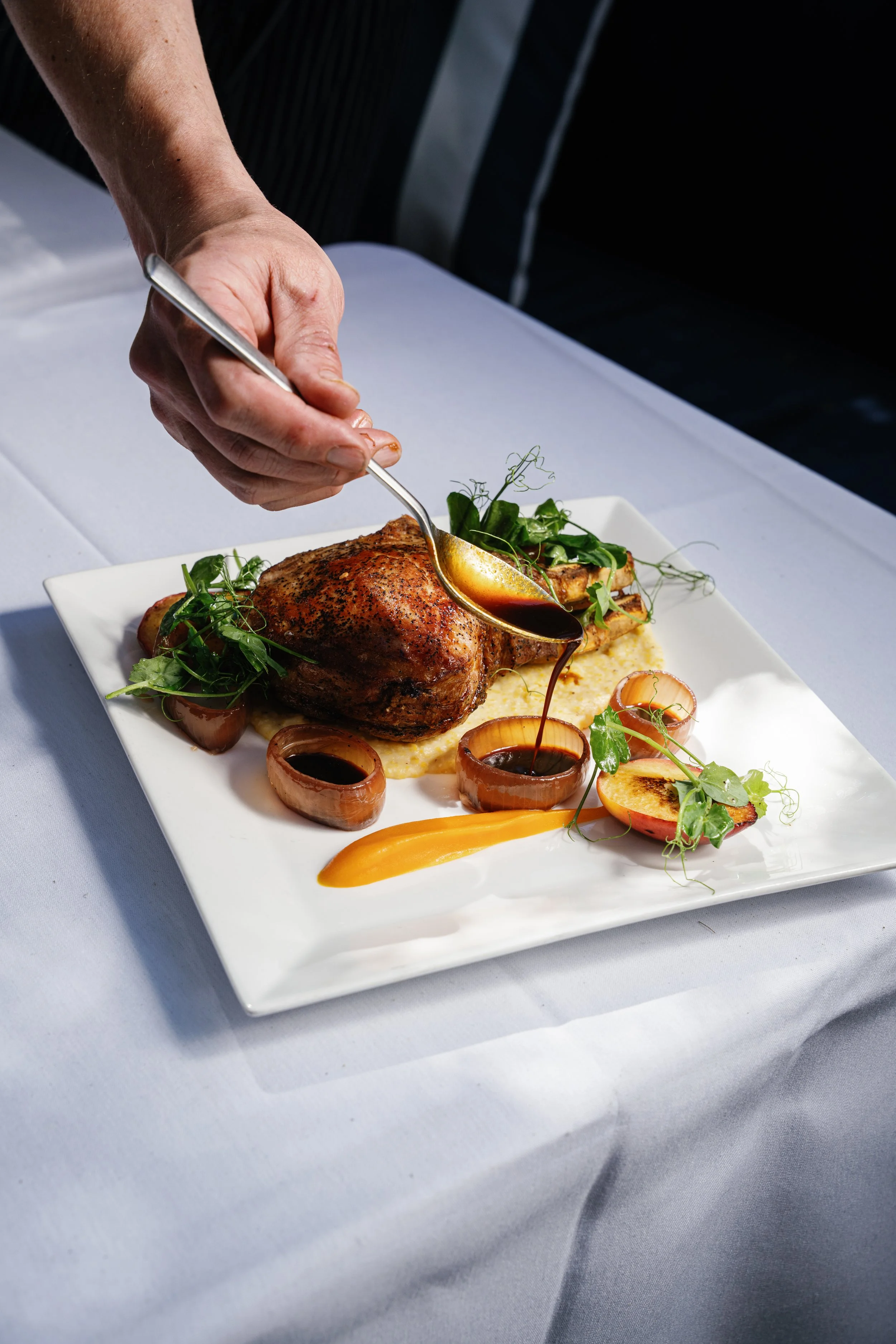 Chef Mark Connell putting the finishing touches on ZIgzag Aspen's wood-fired pork chop with pine nut sausage stuffing