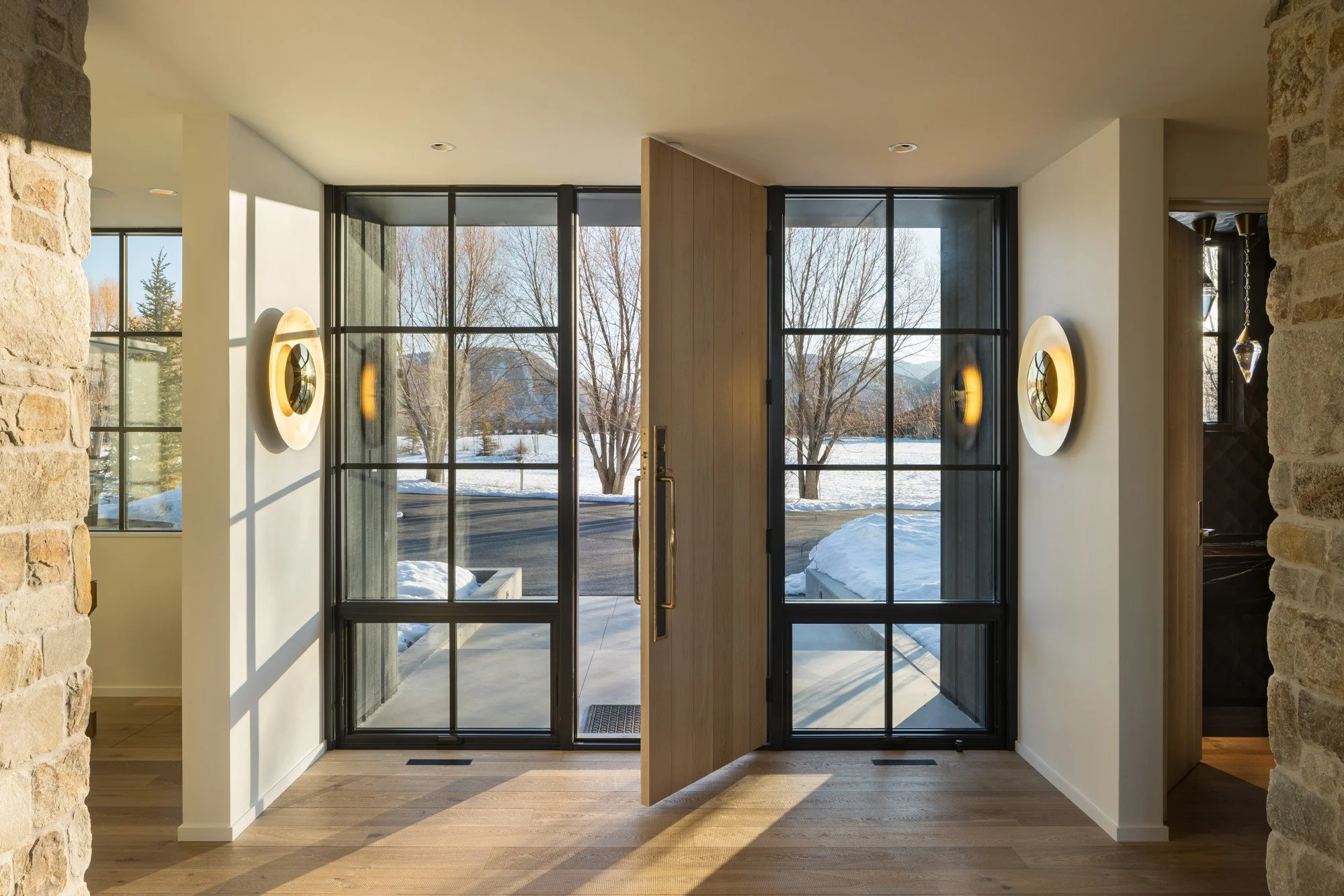 Modern interior entrance with large glass door and snowy landscape view.