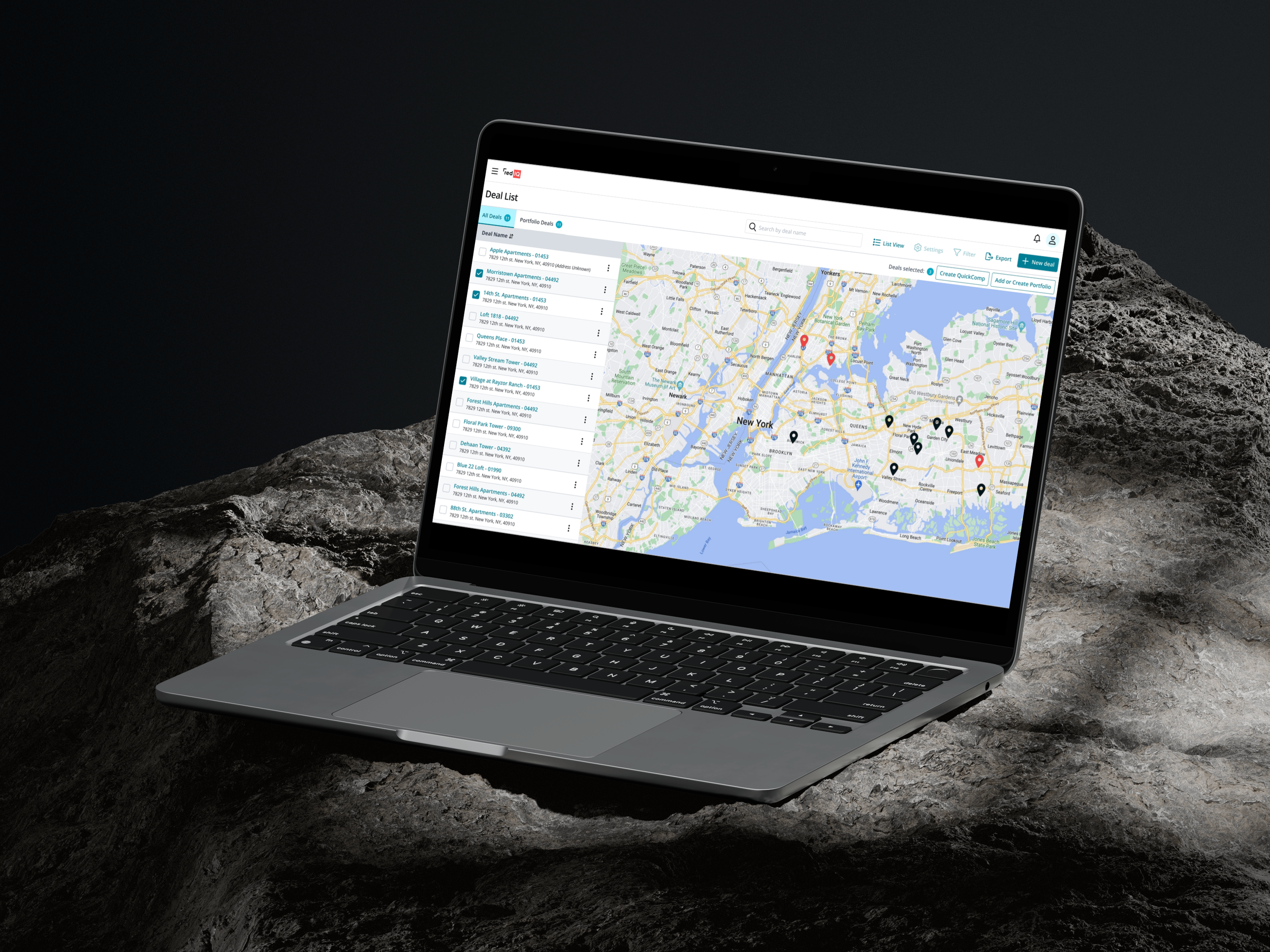 A laptop computer displaying a map of New York City with marked locations and a list of deals on the screen, sitting on a rough, rocky surface with a dark background.