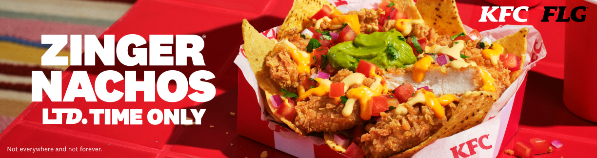 KFC Zinger Nachos in a red container topped with fried chicken, cheese, guacamole, diced tomatoes, onions, and tortilla chips on a red surface.