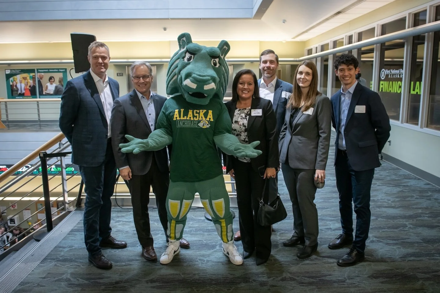 Chancellor Sean Parnell and employees from McKinley Management post with Spirit, the Seawolf mascot, on the second floor of Rasmuson Hall.