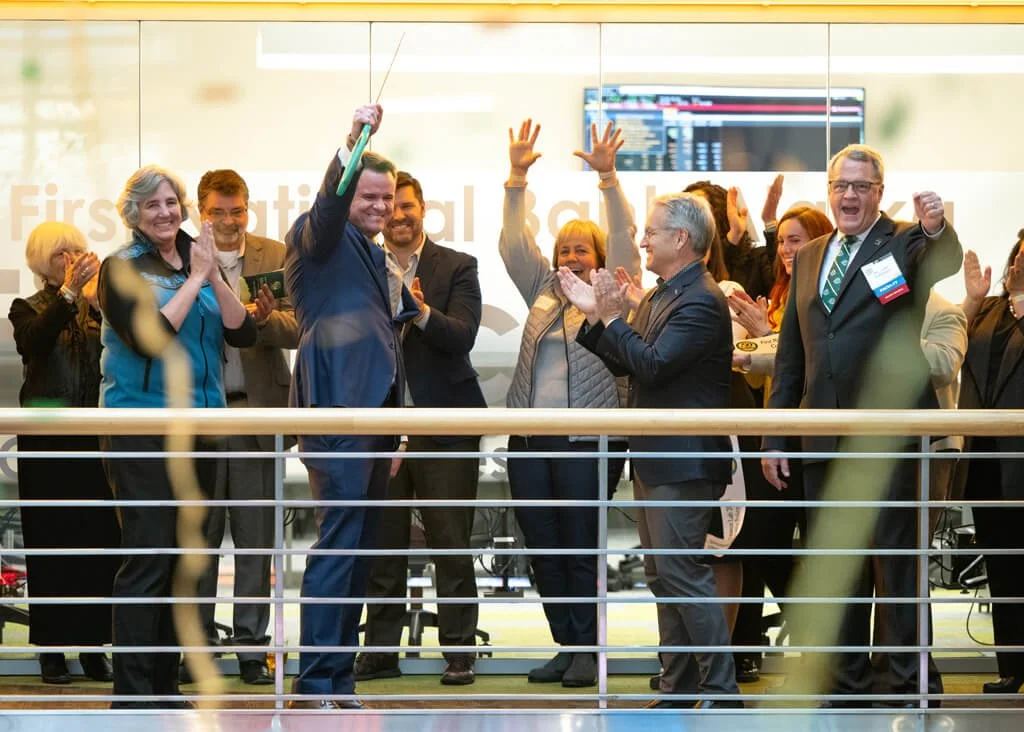 A group of people celebrate on the second floor of Rasmuson Hall with streamers in foreground.