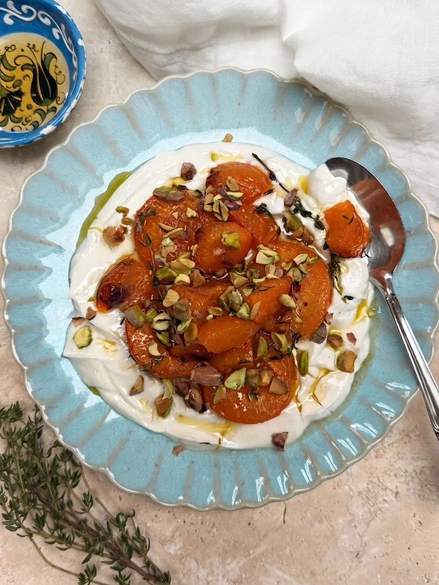 baked apricots on greek yoghurt served on a blue plate and topped with pistachios