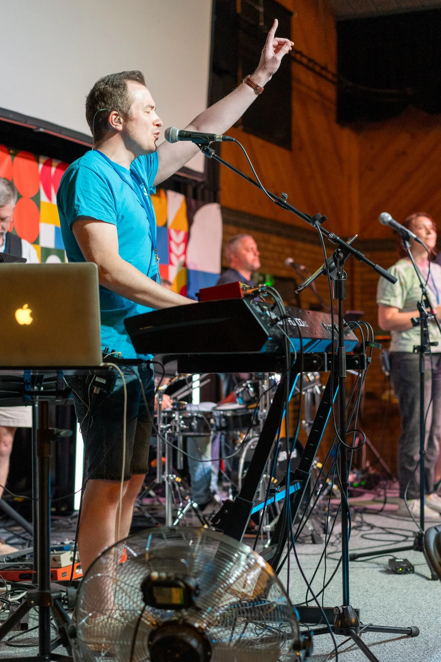 man raises hand while singing and playing instrument