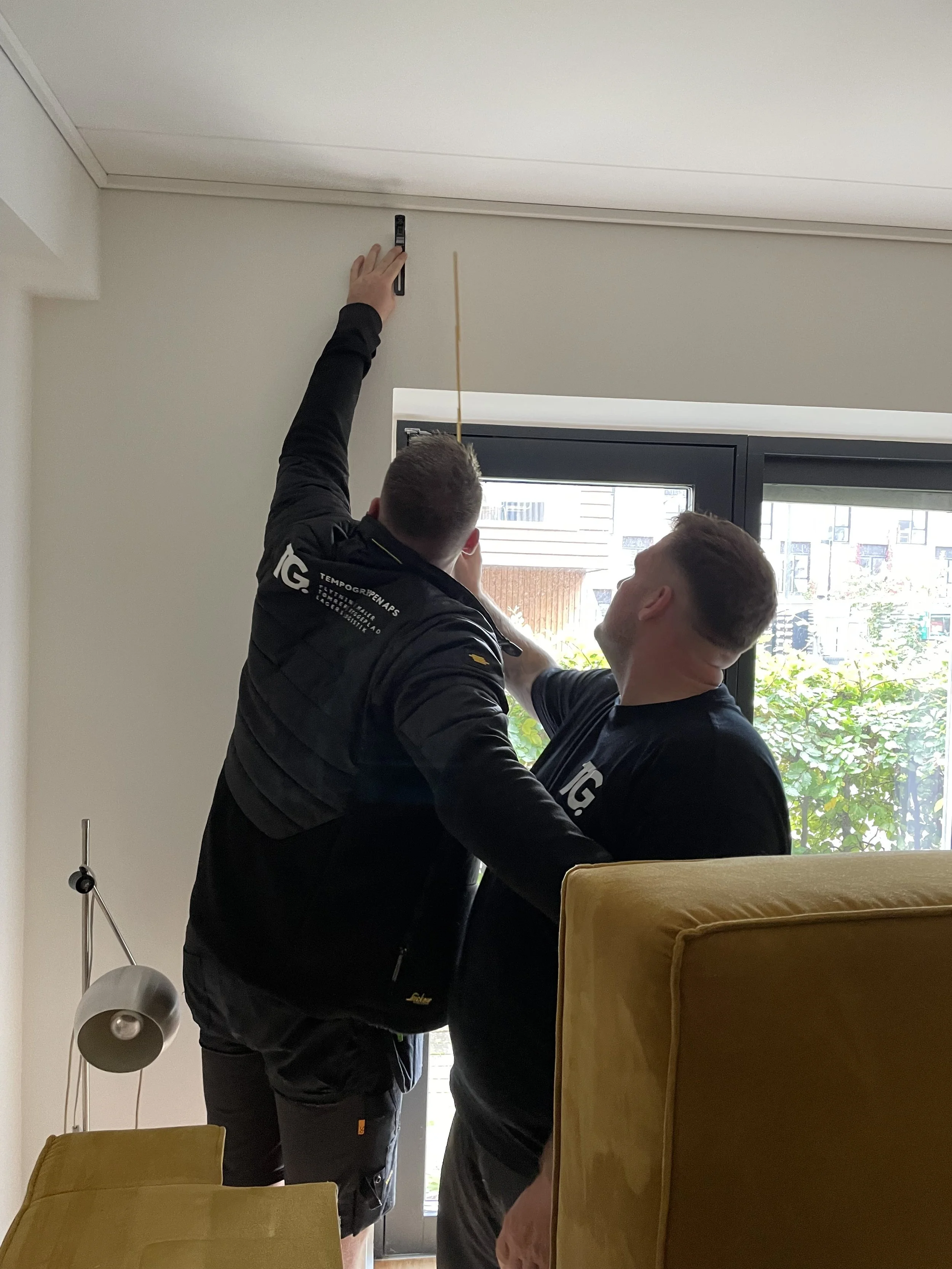 To mænd installerer et stikkontakt eller en impdning i loftet indendørs.