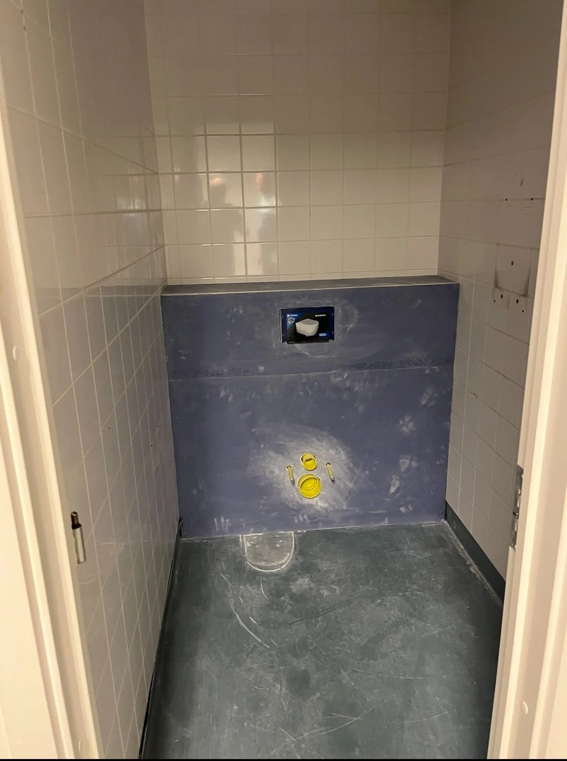 Stue under renovering med væg og gulv, og installationer til toilet.