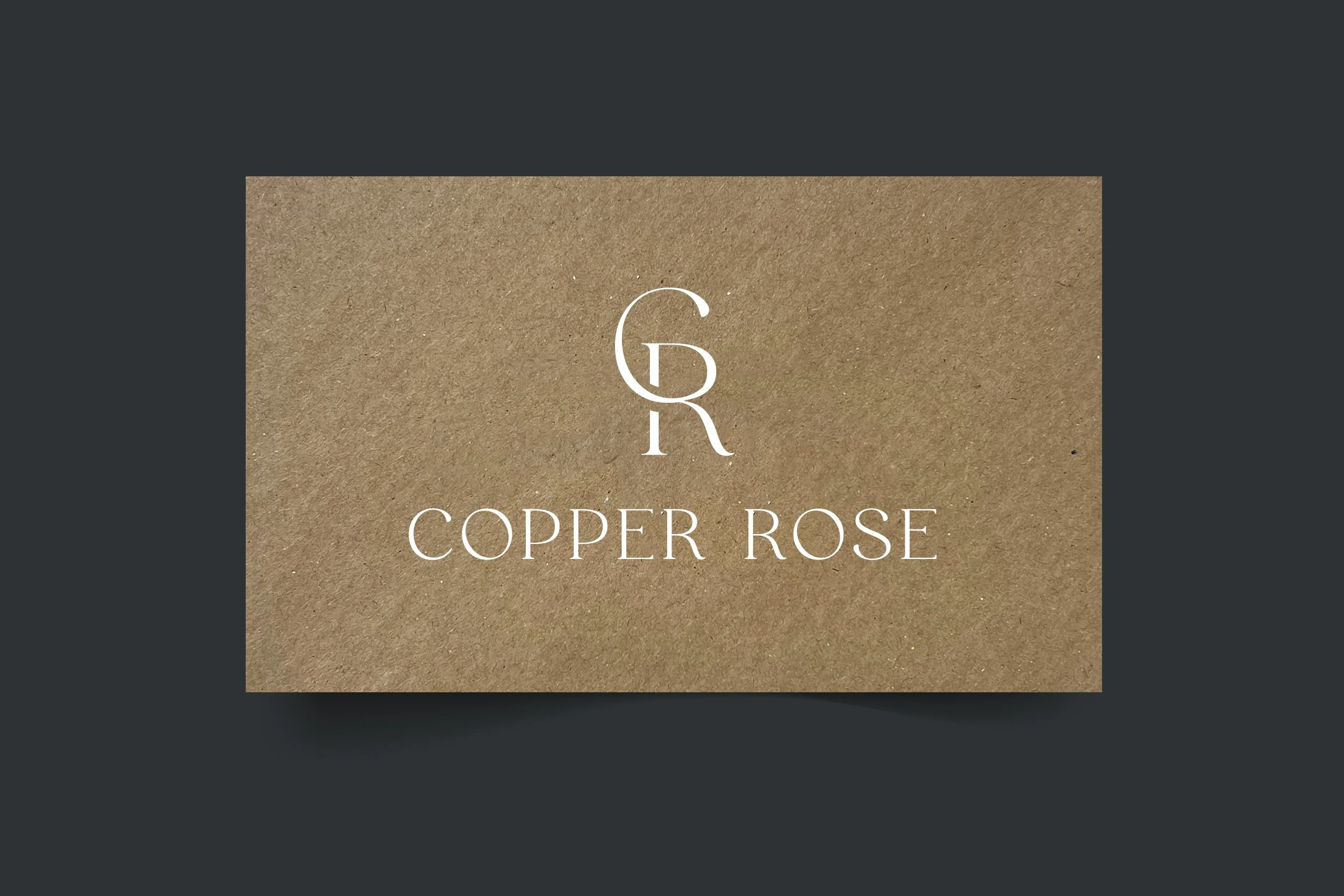 Business card with a brown textured background displaying the logo 'GR' and the text 'Copper Rose' in white.
