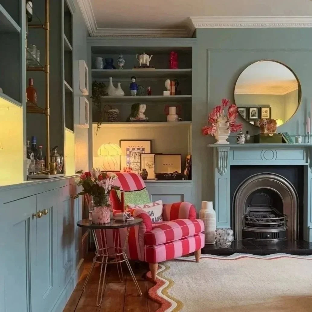 Colourful Cotswolds sitting room with pink chair and layered interiors by Birdie & Co