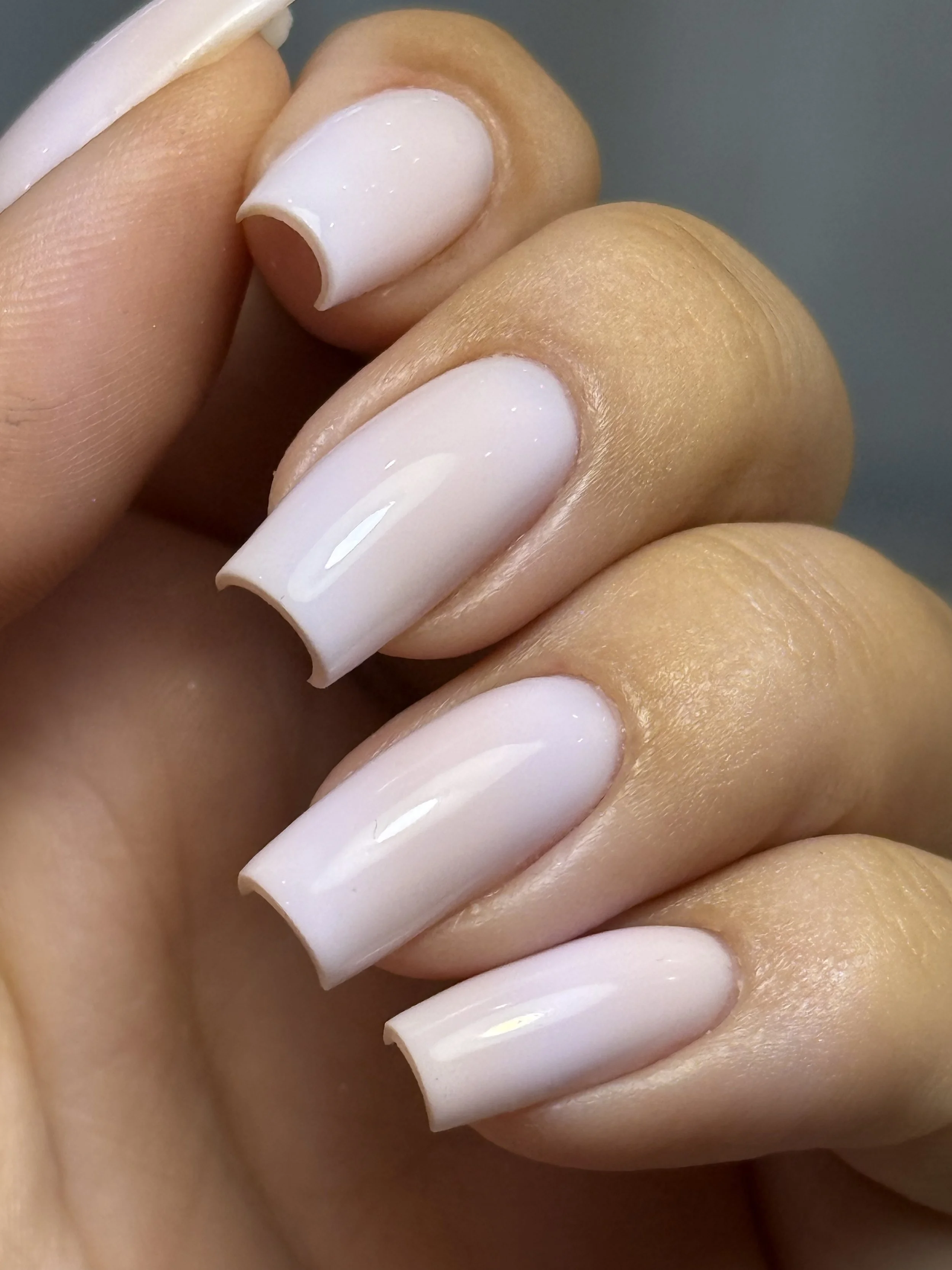 Close-up of a woman's hand with neatly manicured nails painted in light pink or nude color.