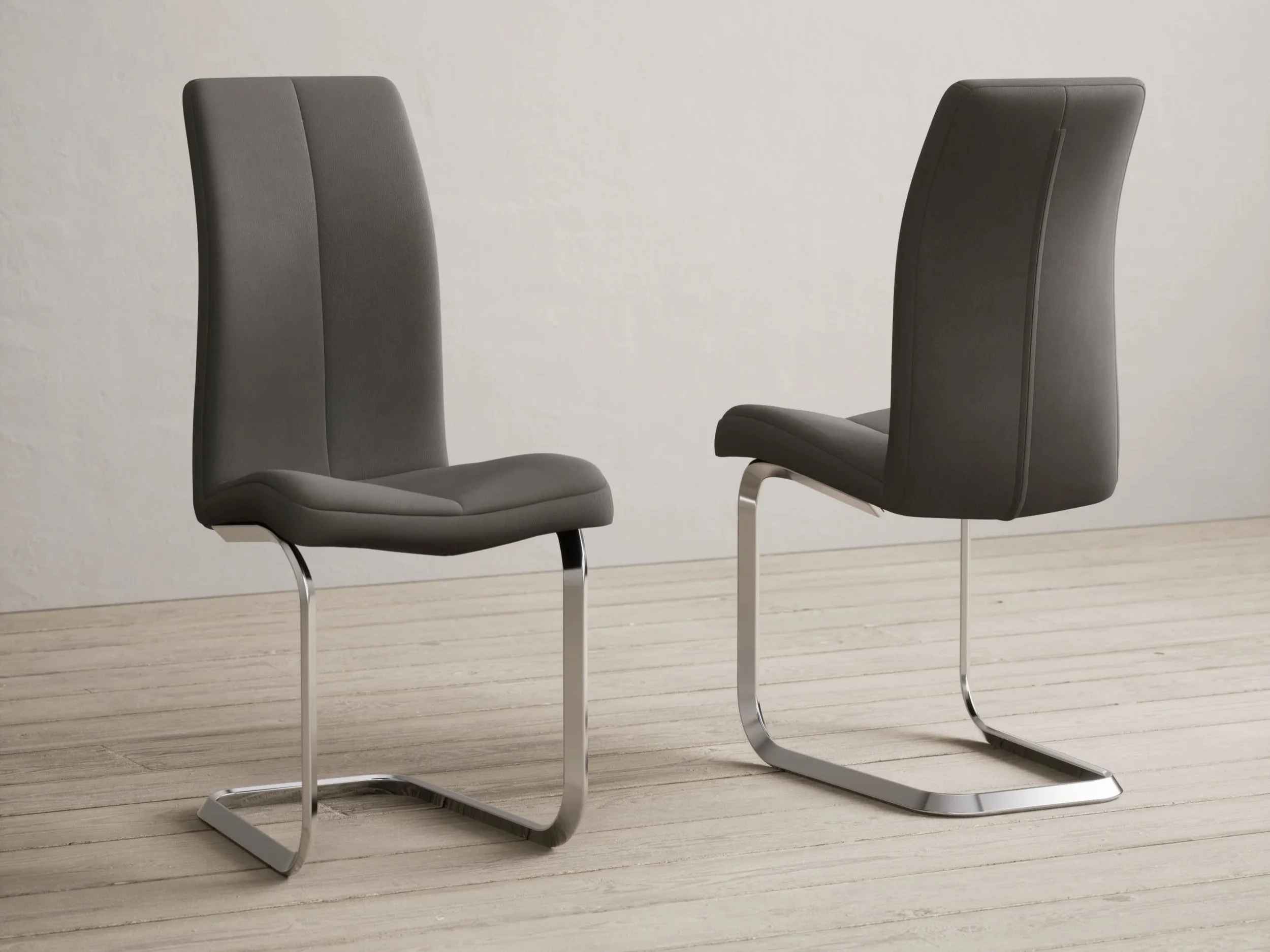 Two modern black office chairs with metal sled bases on a light wooden floor against a plain off-white wall.