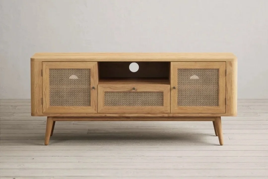 A mid-century modern wooden TV stand with three drawers, two with rattan fronts, on a light wood floor in front of a plain wall.