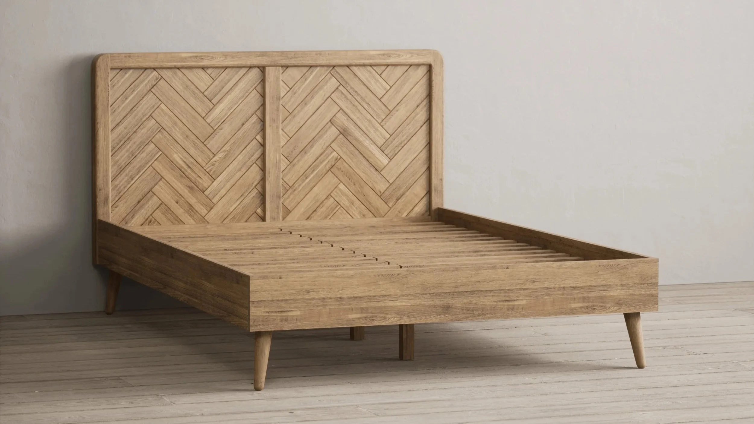 Empty wooden bed frame with a herringbone-patterned headboard and tapered legs, set against a plain wall and wood floor.