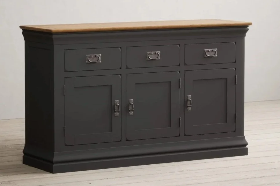 A black wooden sideboard with three drawers on top and three cabinet doors below, standing on a light-colored floor against a white wall.