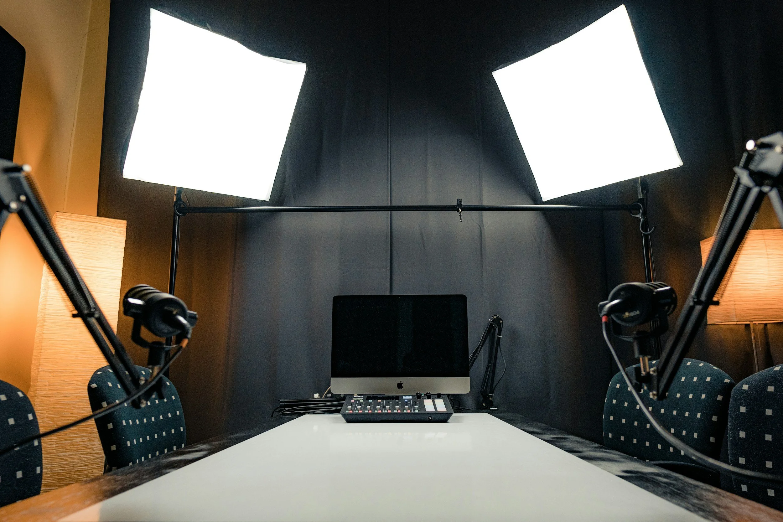 Een vergadertafel met vijf stoelen en opnameapparatuur inclusief microfoons en lampen in een studio of vergaderruimte.