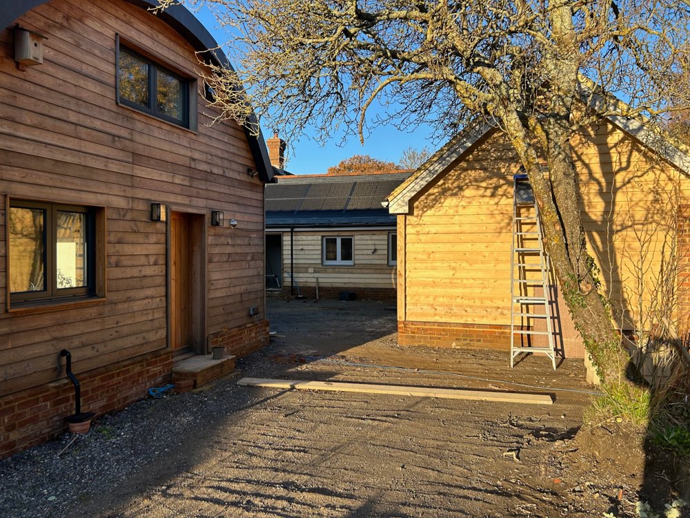 View of three wooden houses with a tree in a backyard during daylight, with construction work ongoing.
