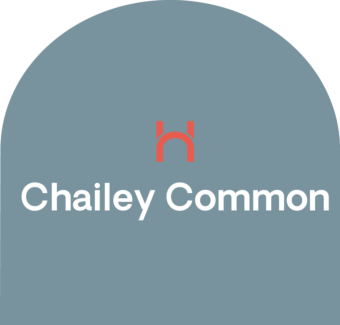 Sign for Chailey Common with a stylized red hiker icon above the text in white on a blue background.