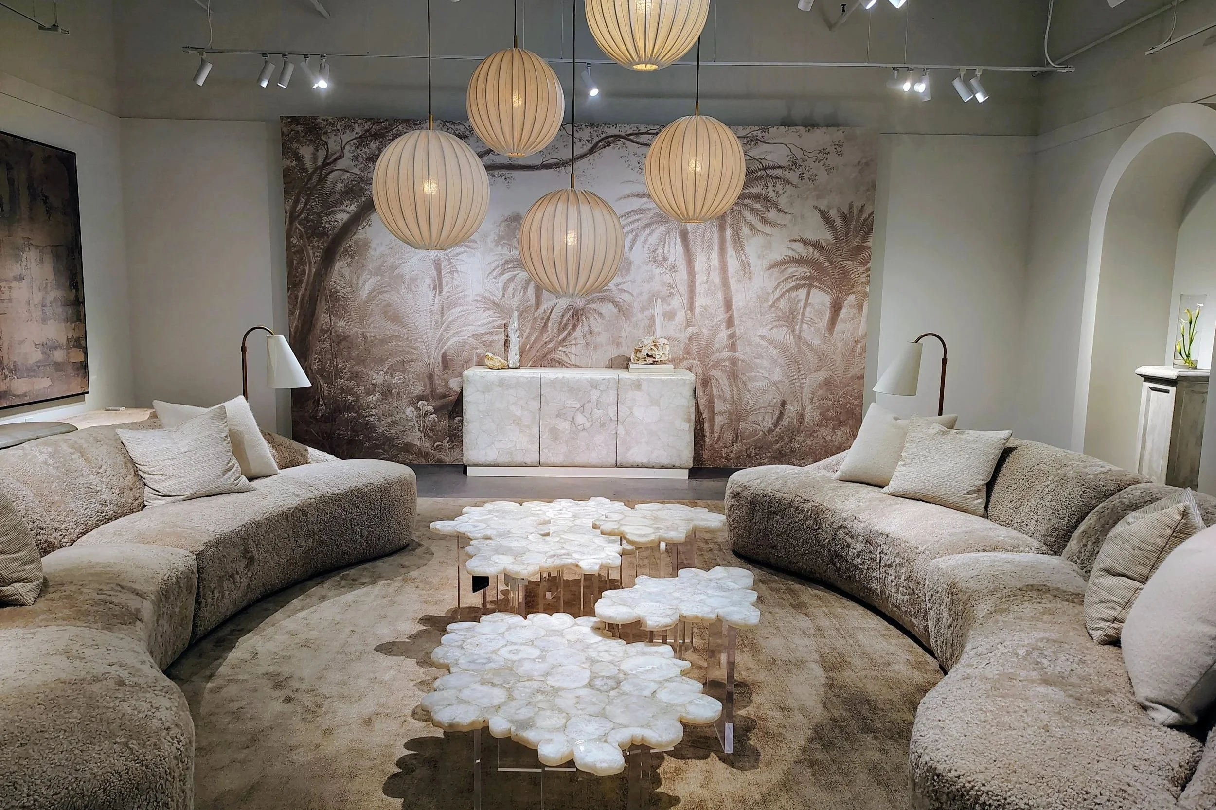 Living room with large sectional sofa, tea table, wall mural with trees, pendant lights, and lamps.