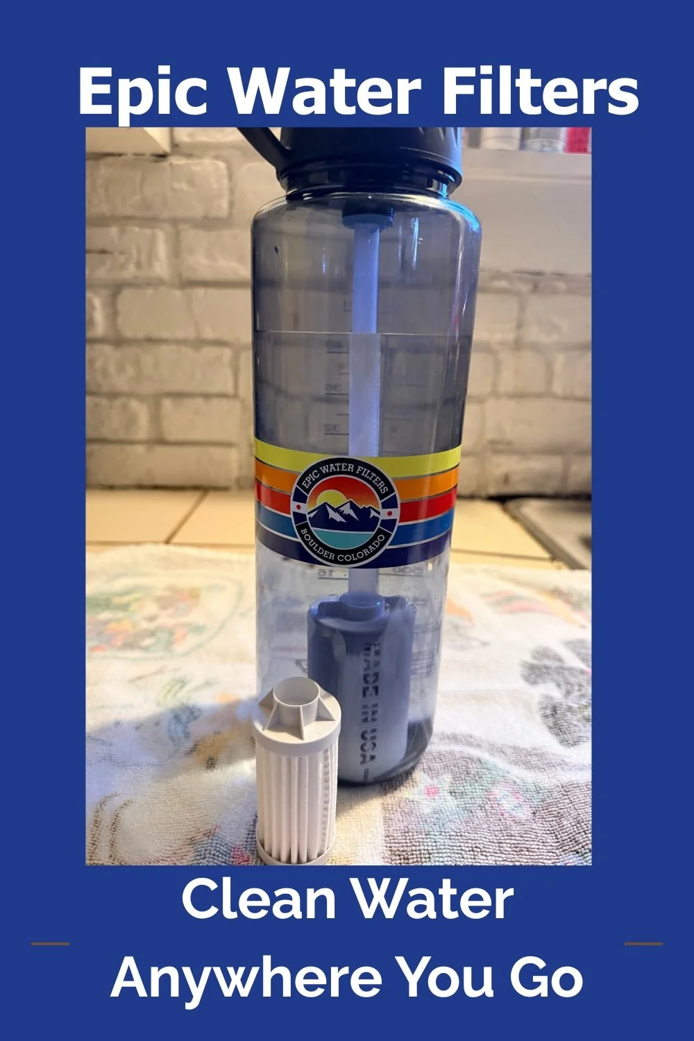 A water filter pitcher with a sticker that says "Epic Water Filters Boulder Colorado" and a filter cartridge in front of it, on a cloth surface with a brick wall background, with text saying "Epic Water Filters" at the top and "Clean Water Anywhere You Go" at the bottom.