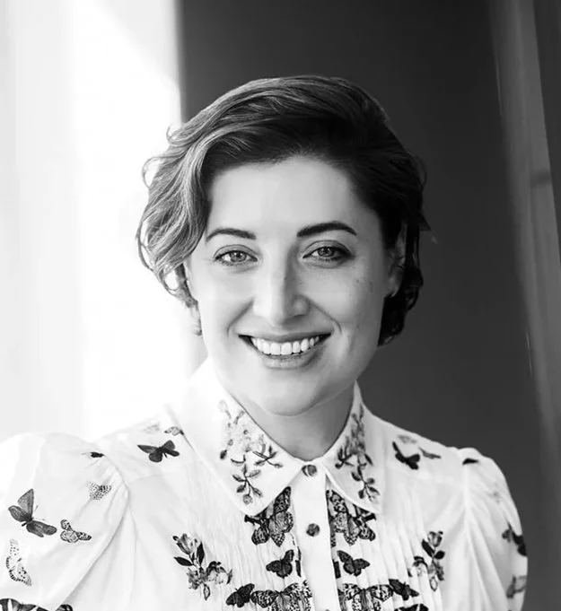 Black and white portrait of a woman with shoulder-length hair and bangs, smiling slightly, wearing a collared shirt.