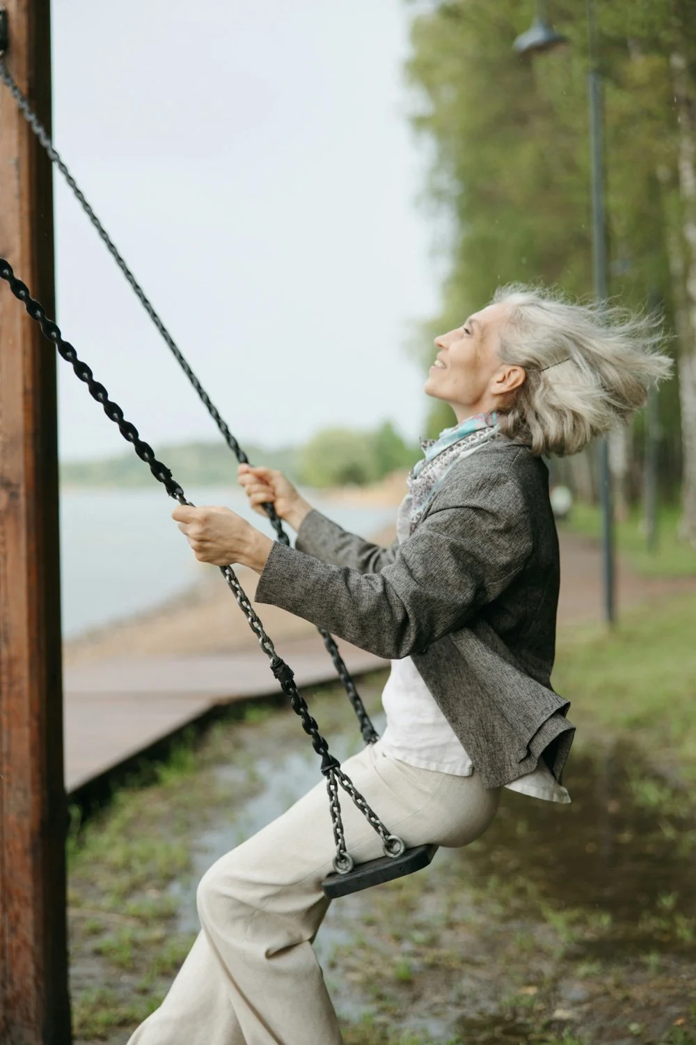 a smiling older woman swings on a swing