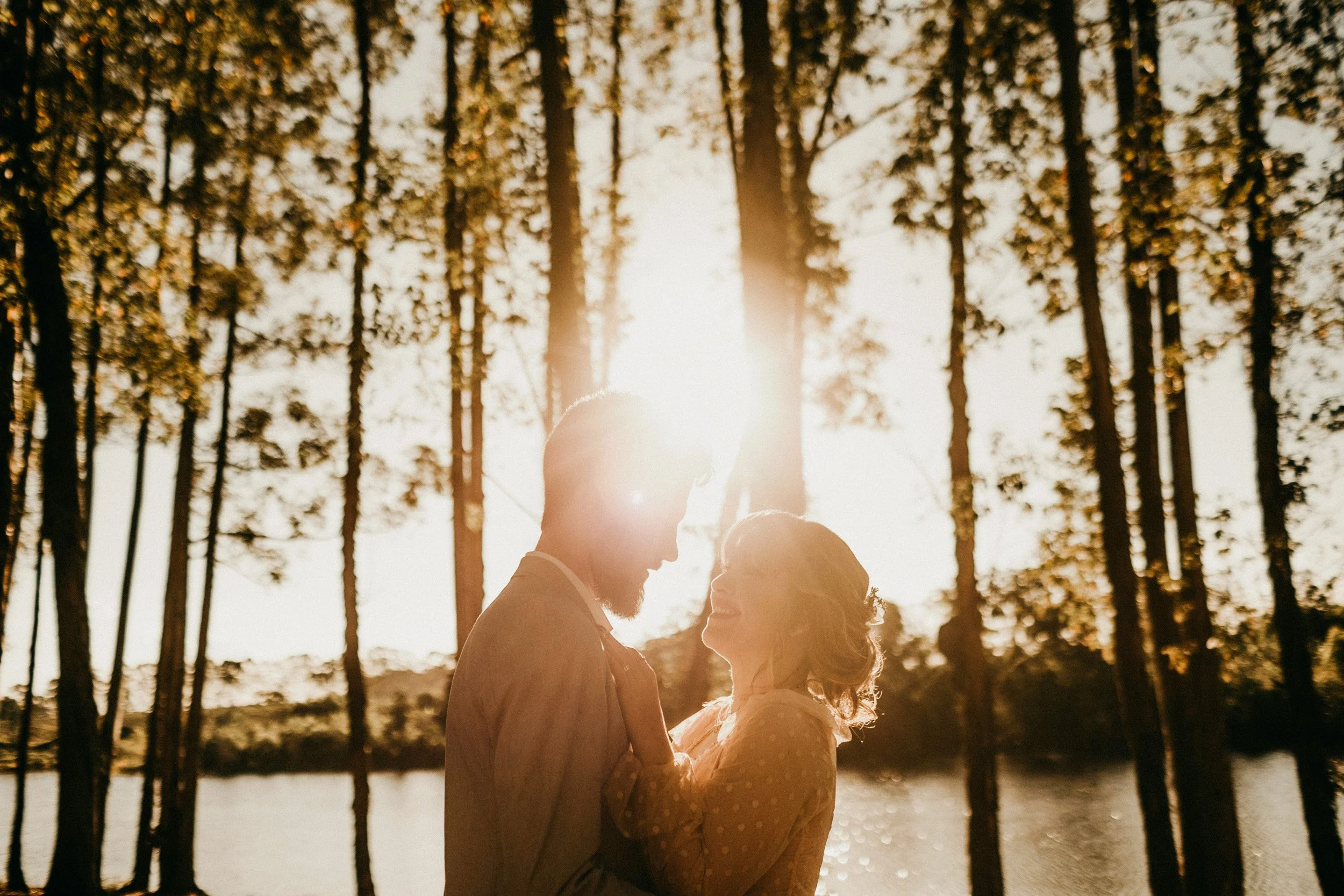a happy couple embraces in a sunlit natural setting