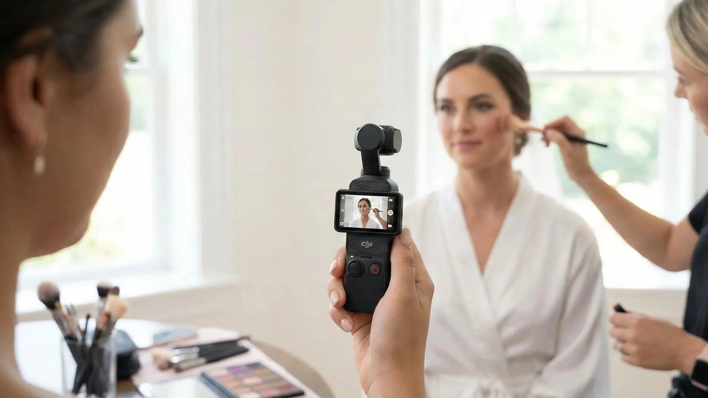 Bride having makeup applied while a friend films