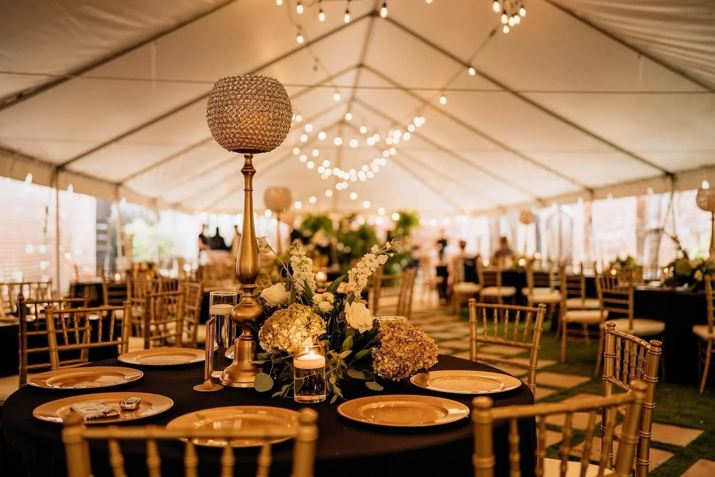 Wedding tent with Chivari chairs and gold chargers.