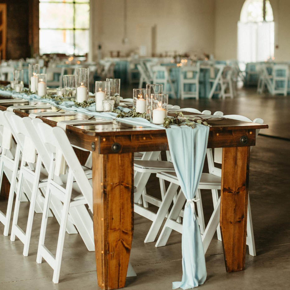 Wedding reception decor featuring white candles on long wooden tables inside the Da Vinci Room event space