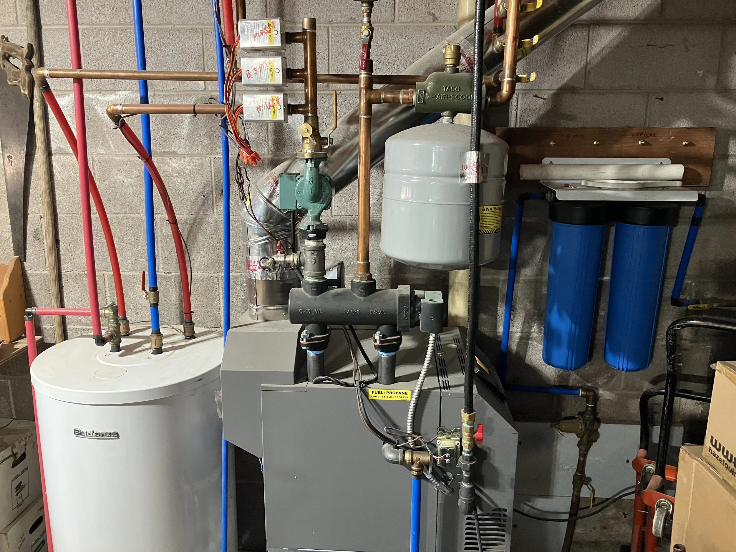 Indoor mechanical room with water filtration system, pipes, tanks, and filters.