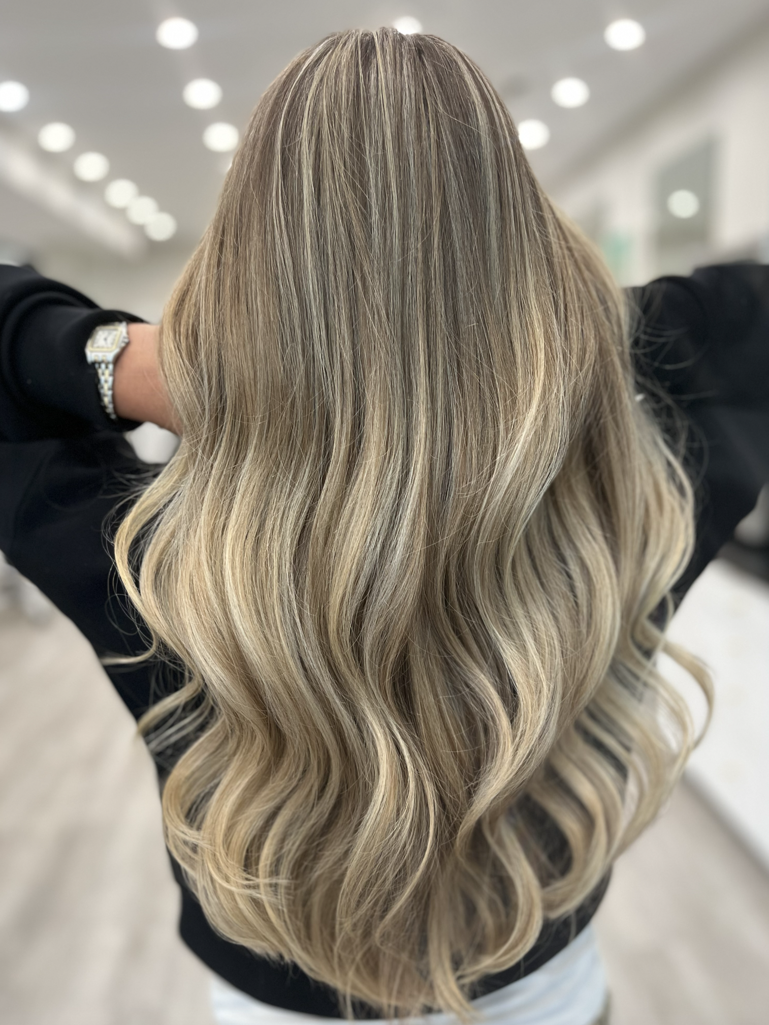 Person with long, wavy, blonde hair in a salon setting.