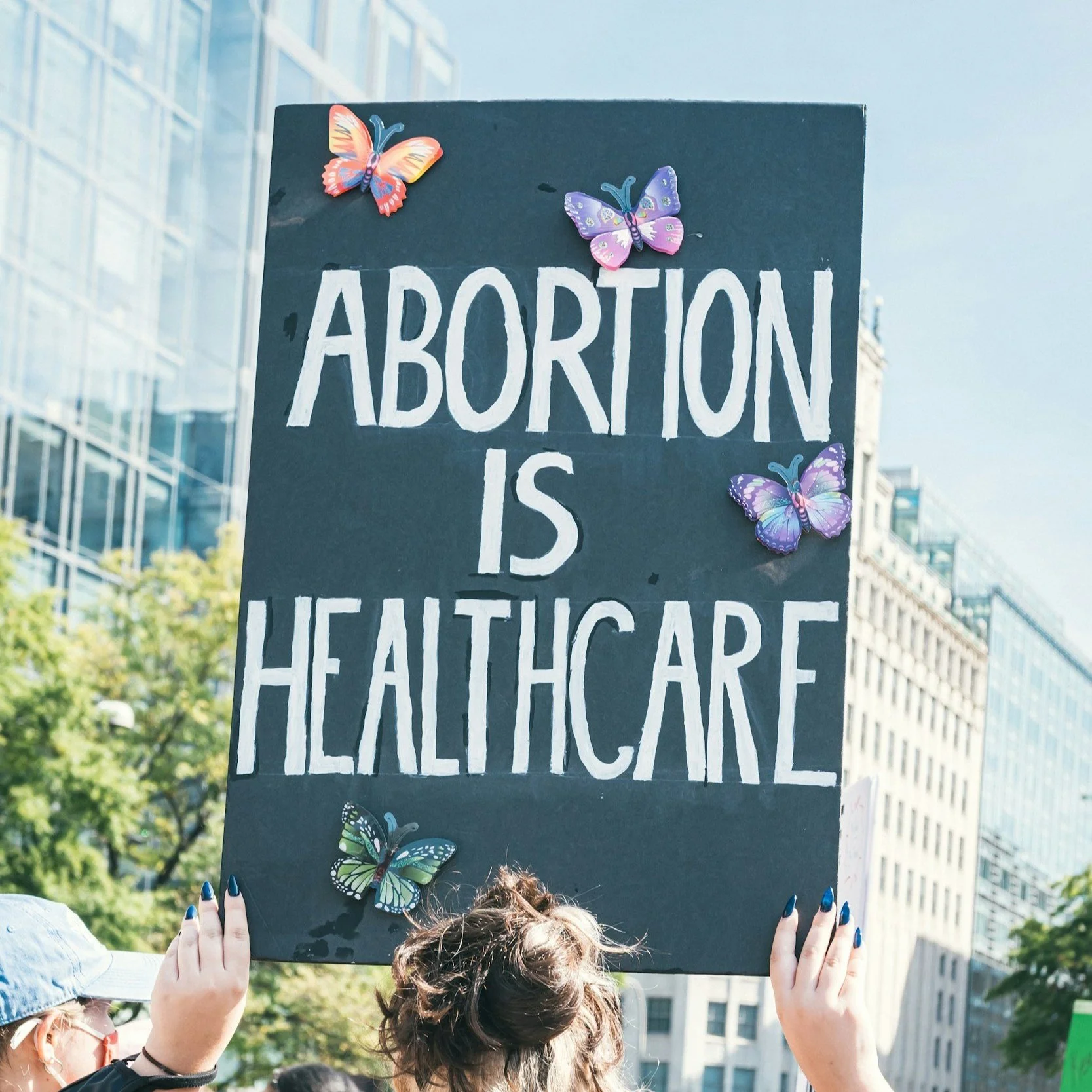 A protest sign that reads "Abortion is Healthcare" illustrating Karli K Coaching's values of bodily autonomy and women's rights advocacy in sex and relationship coaching.
