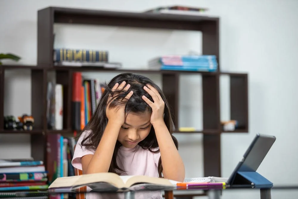 Girl with ADHD frustrated while doing her homework - Homework Battles and ADHD: Why They Happen and What Helps