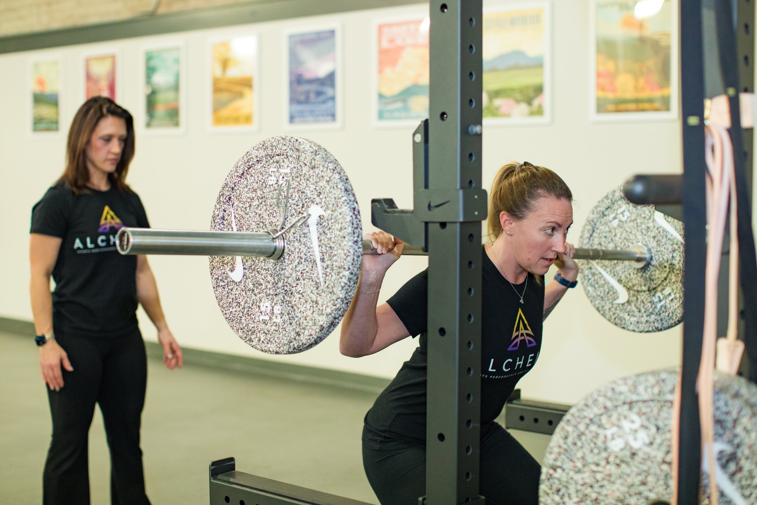 Physical therapist working with patient, patient is doing barbell squats