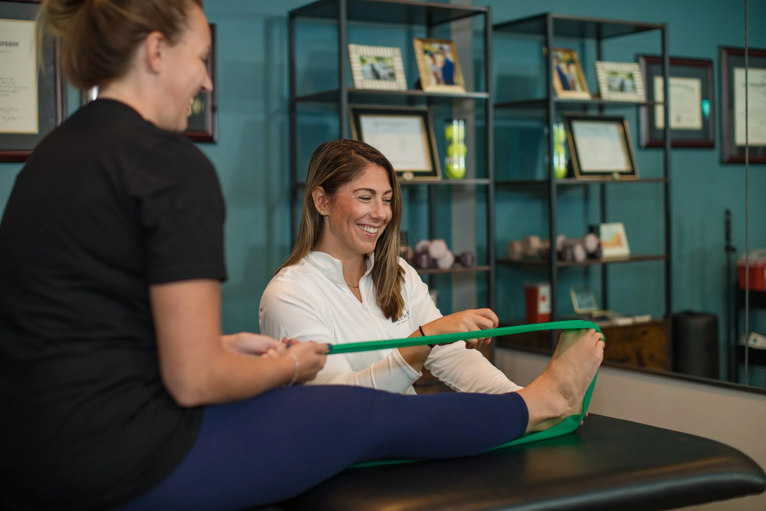 Deanna helping someone exercise using a resistance band