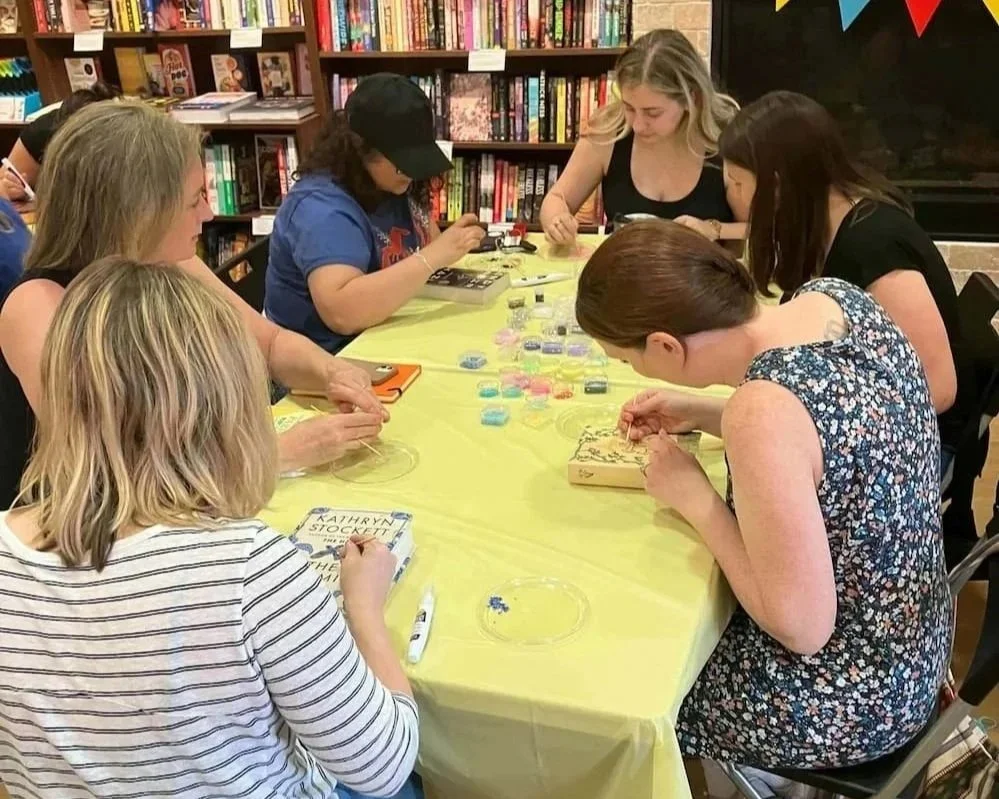 people bedazzling books in library with yellow table cloth