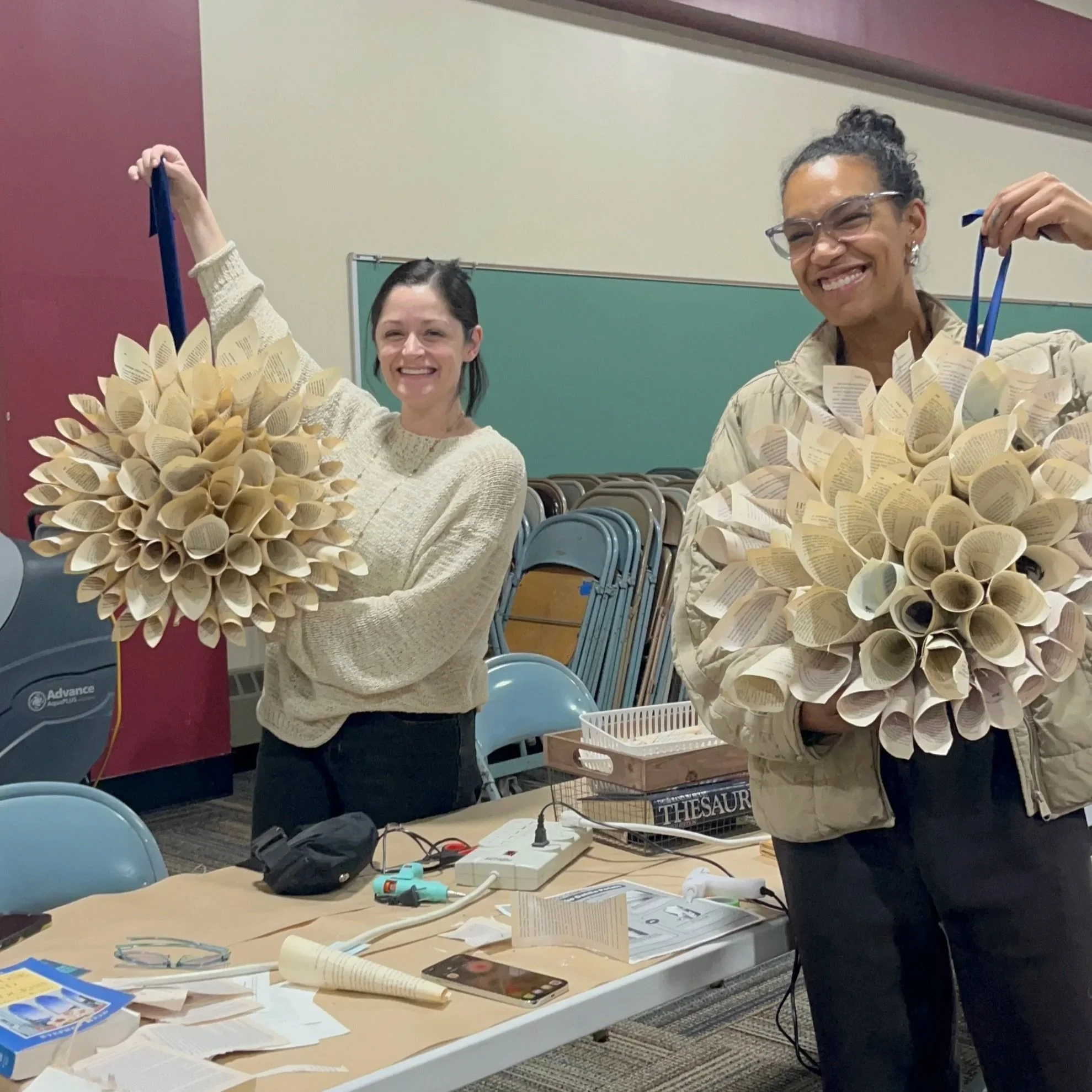two ladies smile holding dahlia paper wreath