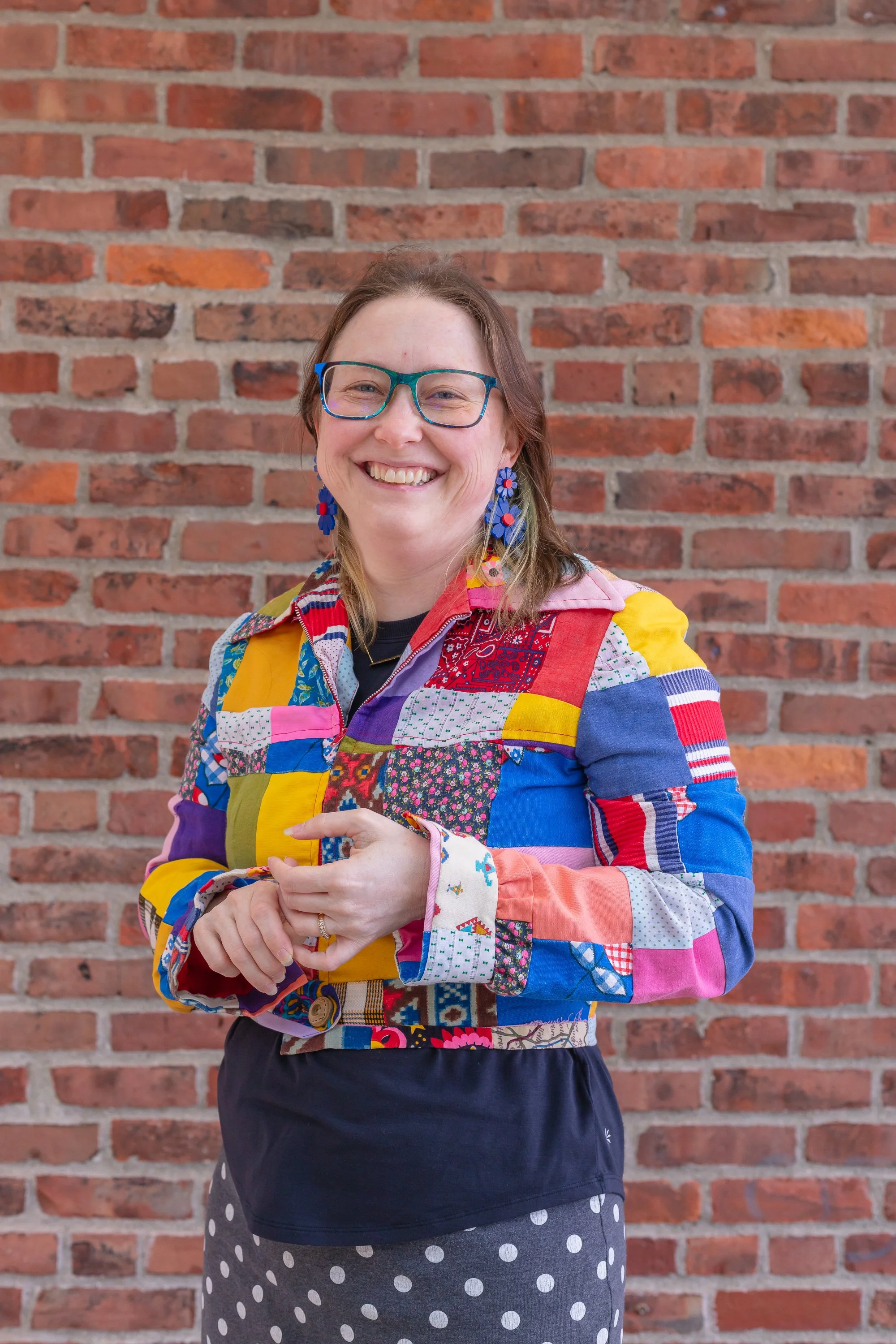 patchwork jacket cynthia mcmullen is standing in front of red brickwall holding her hands slightly