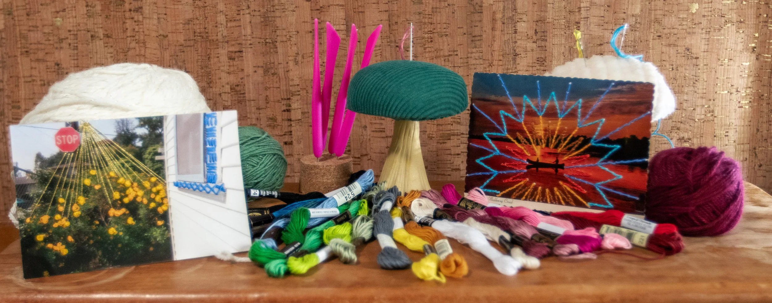 embroidery threads in front of a cork background. photo embroidery, a mushroom pin cushion