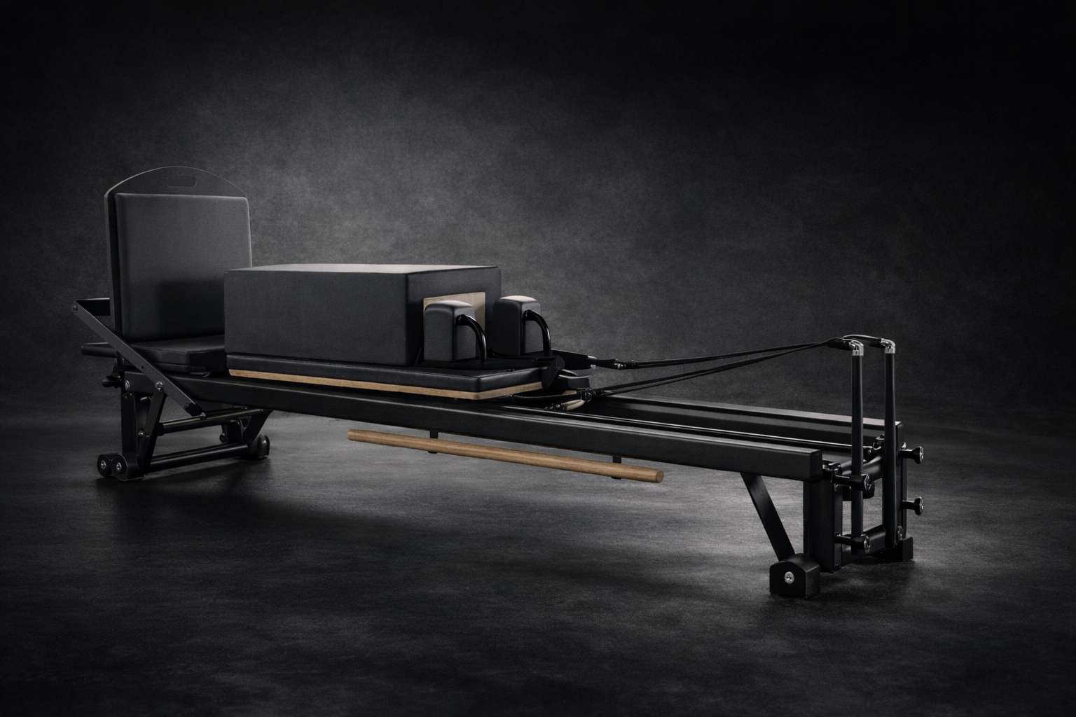A Pilates reformer machine with adjustable components and padding, set against a dark background.