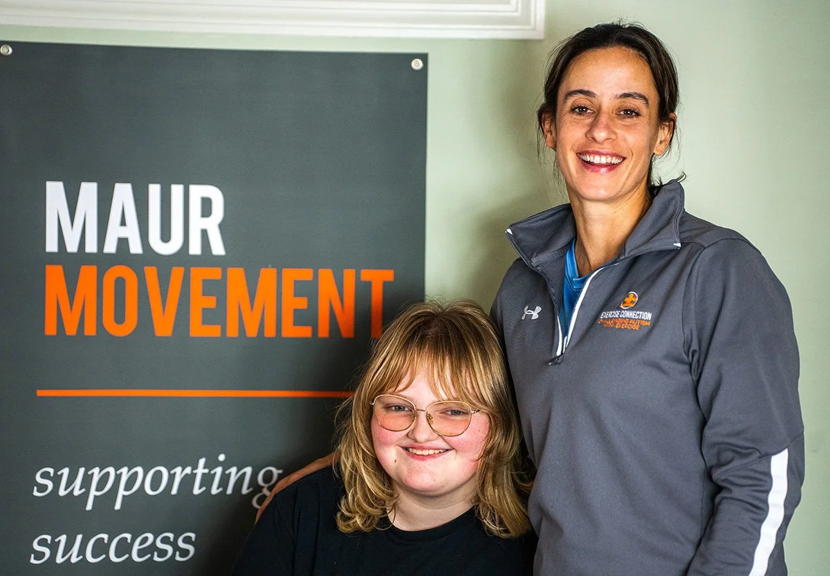 Kristen and student smiling in front of Maur Movement sign