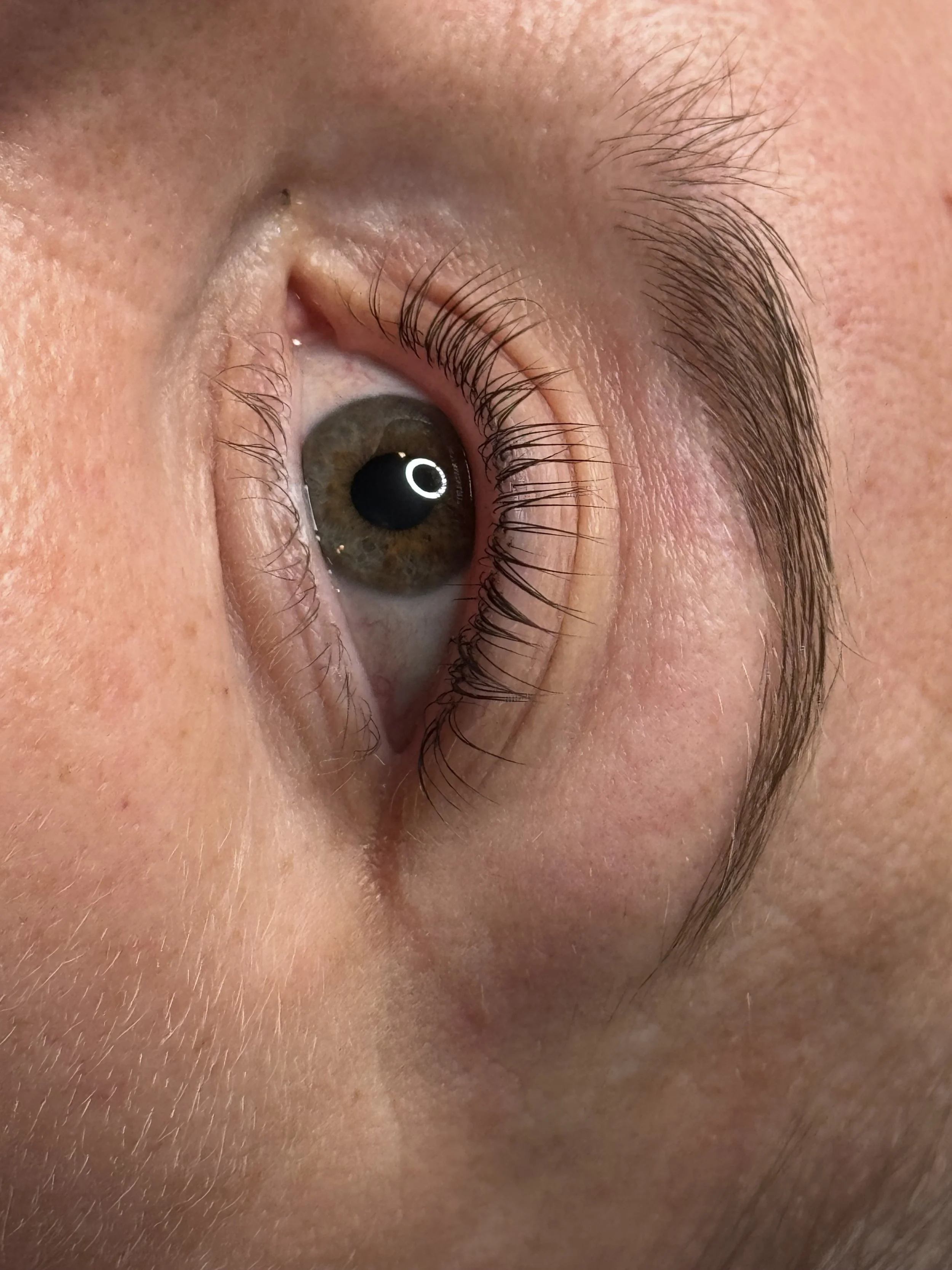 Close-up of a person's eye, showing the iris, eyelashes, and surrounding skin.